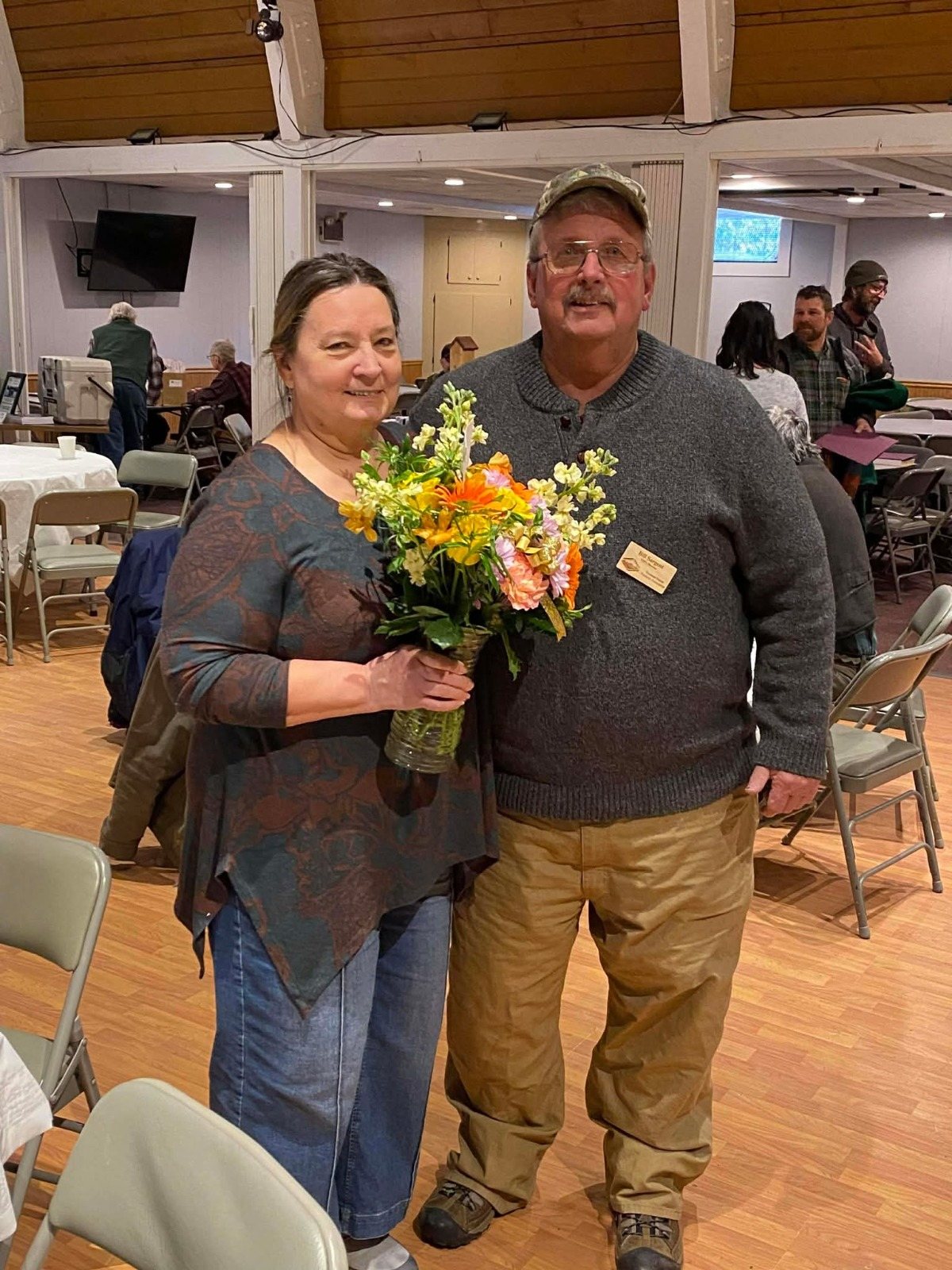 William Sargent with a guest holding a bouquet at an indoor event